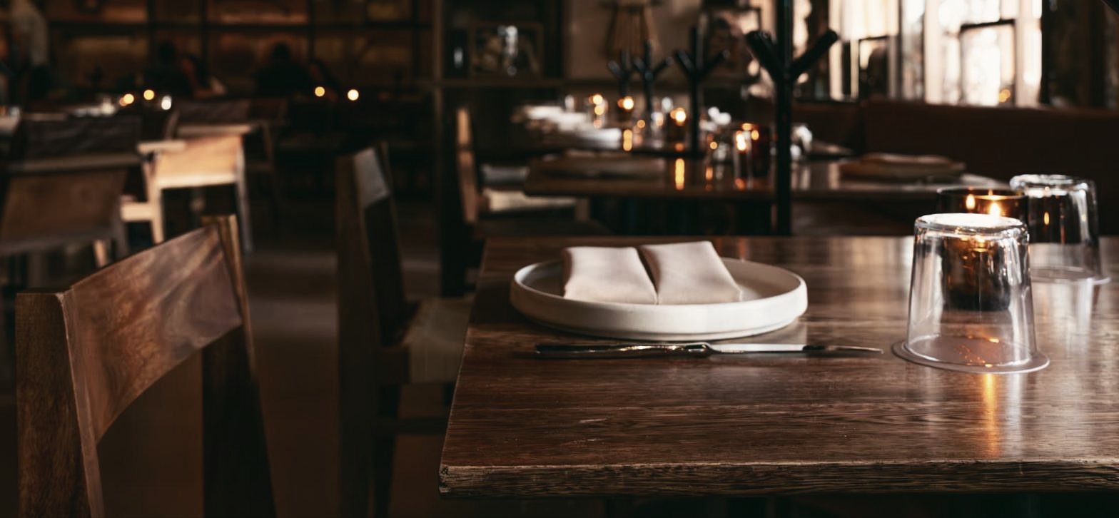 Gedeckter Holztisch in einem Restaurant bei Kerzenlicht